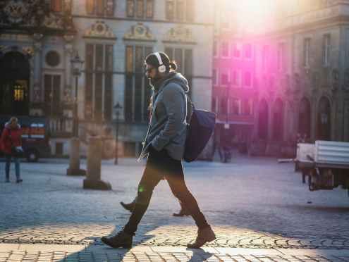 man in gray hooded jacket walking on gray bricks pavement