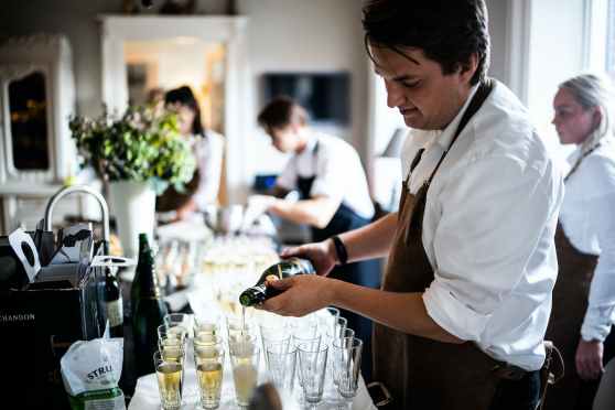 man pouring wine on glasses