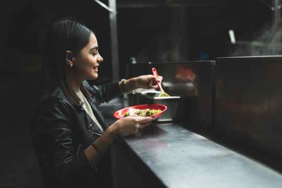 a woman in black leather jacket holding red bowl