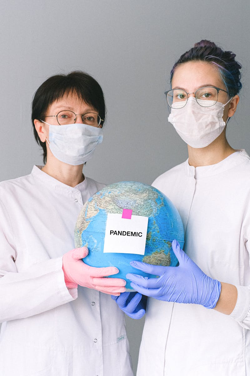 Two healthcare workers holding a globe labeled 'Pandemic', symbolizing global health crisis.
