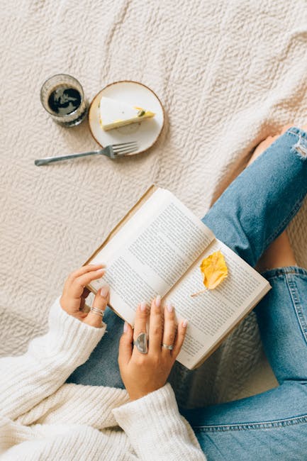 Woman enjoying leisure time at home with a book, coffee, and cheesecake on a cozy blanket.