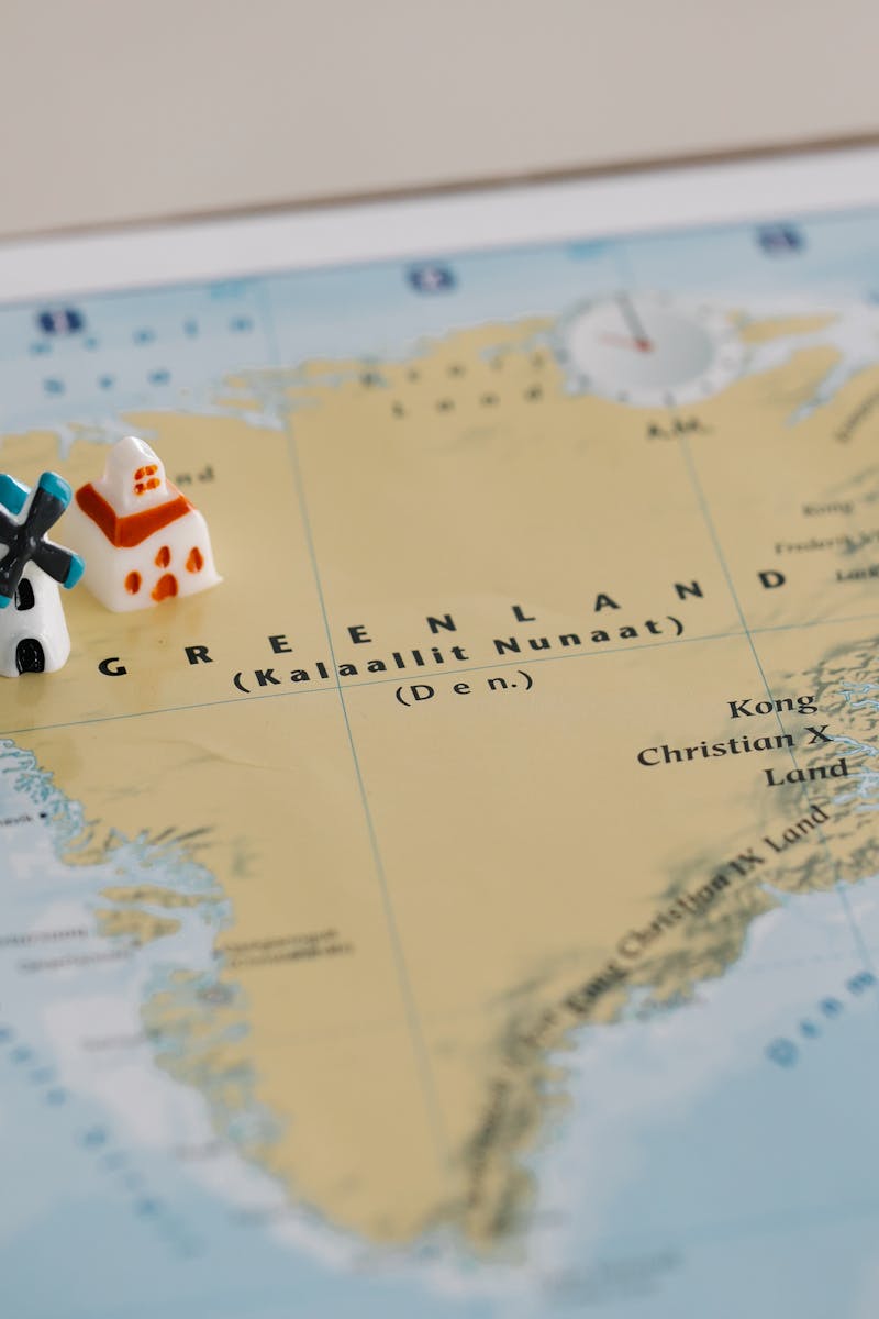 Toy houses on a detailed map of Greenland, highlighting geographic features. Ideal for travel concepts.